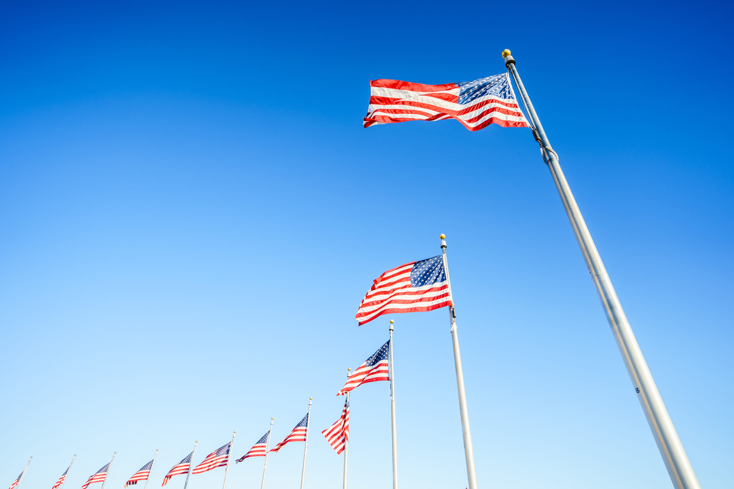 The American flags on flagpoles on blue sky background