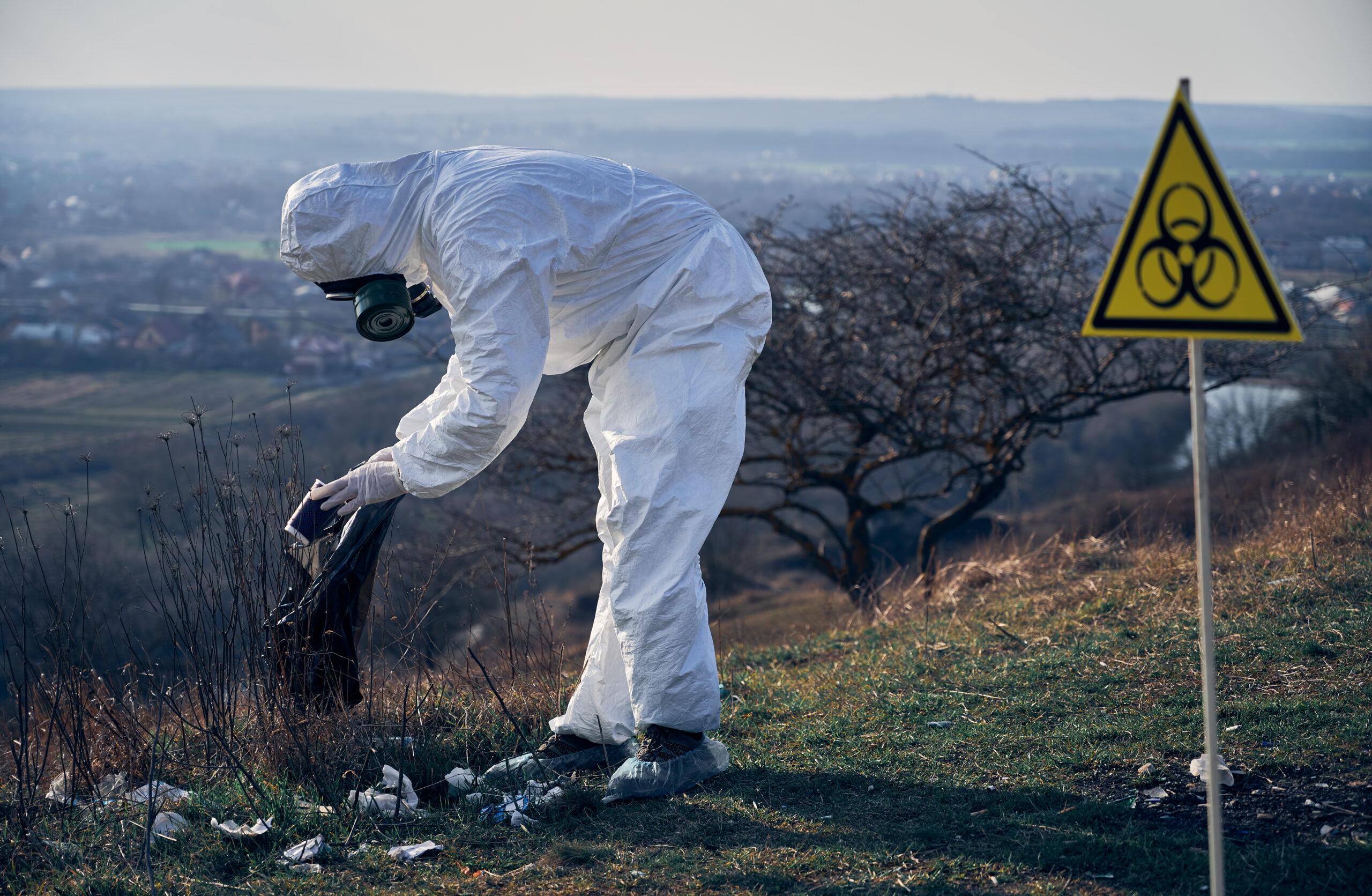 Environmentalist wearing white protective coverall, gas mask, collecting